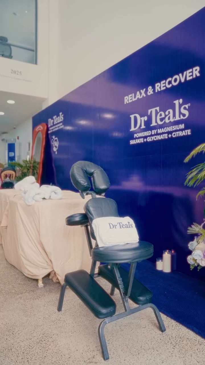 A black pedicure chair with a Dr Teal's towel, against a deep blue RELAX & RECOVER backdrop