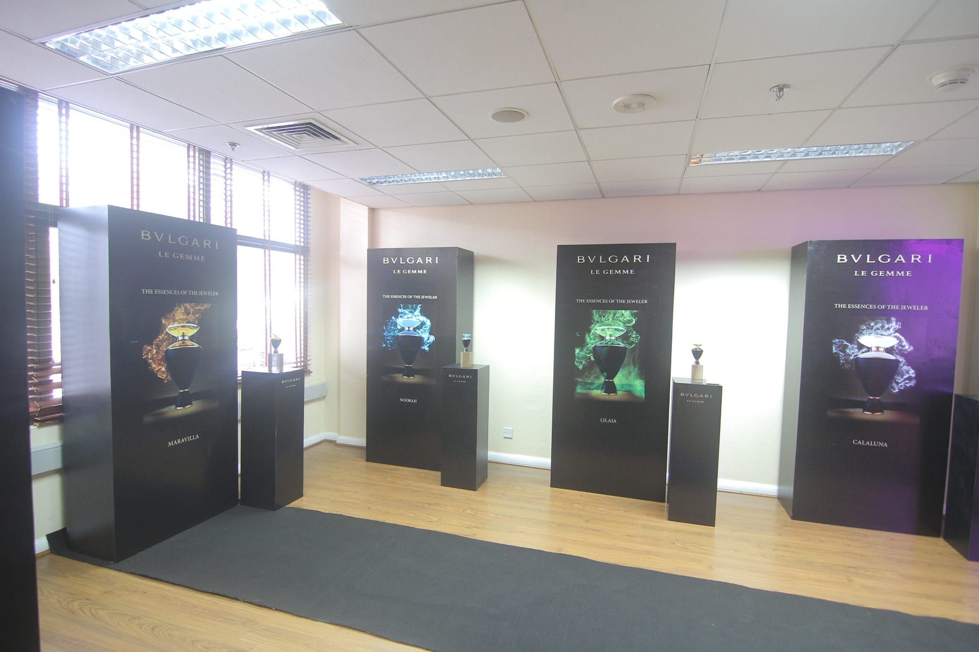 A Bvlgari Le Gemme display standing on a shop floor under ceiling lights, flanked by tall branded panels